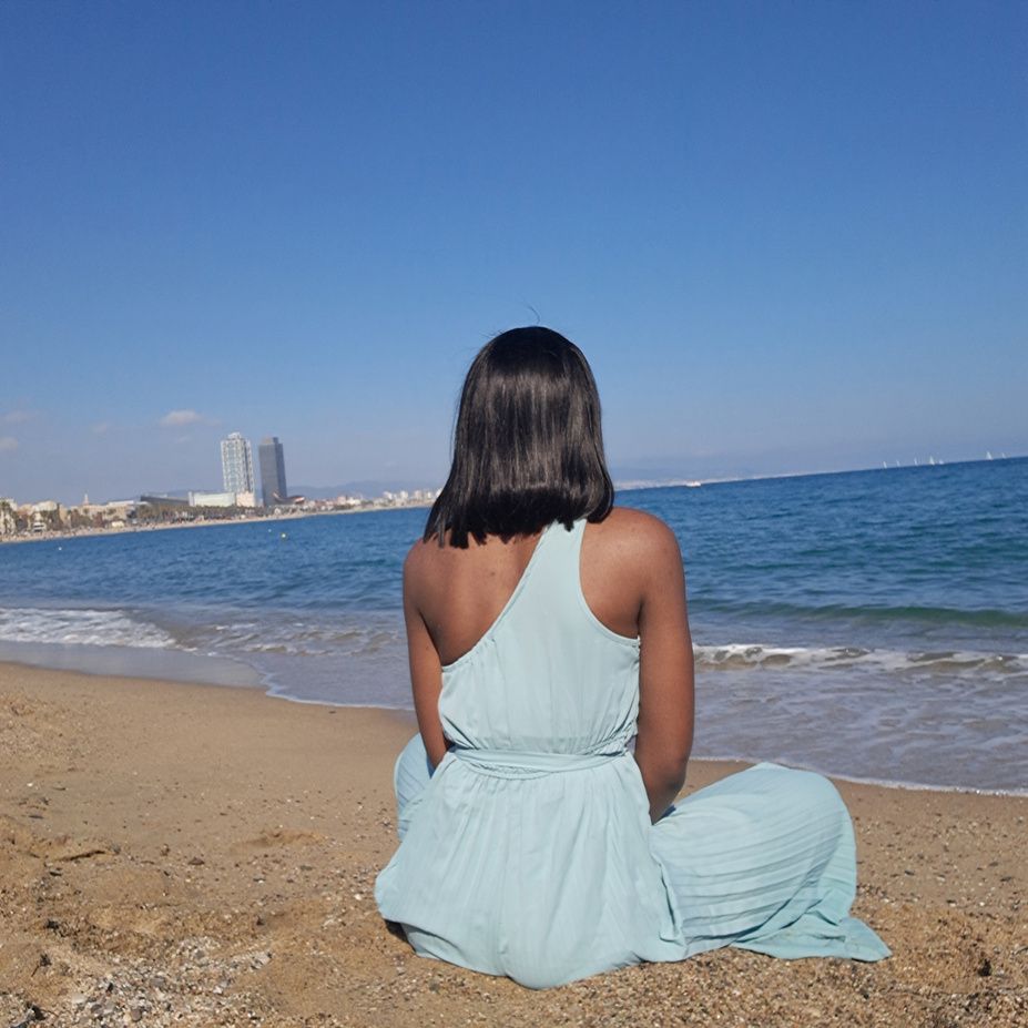 Fifine assise sur la plage face à la mer